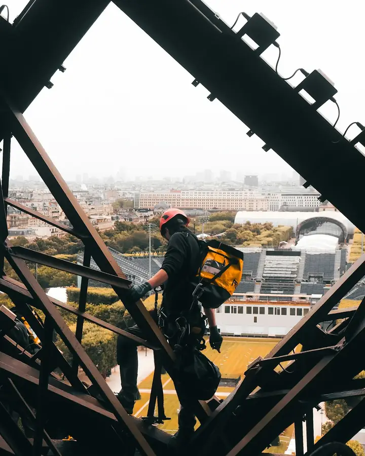Worker in a harness climbing a steel structure above the city