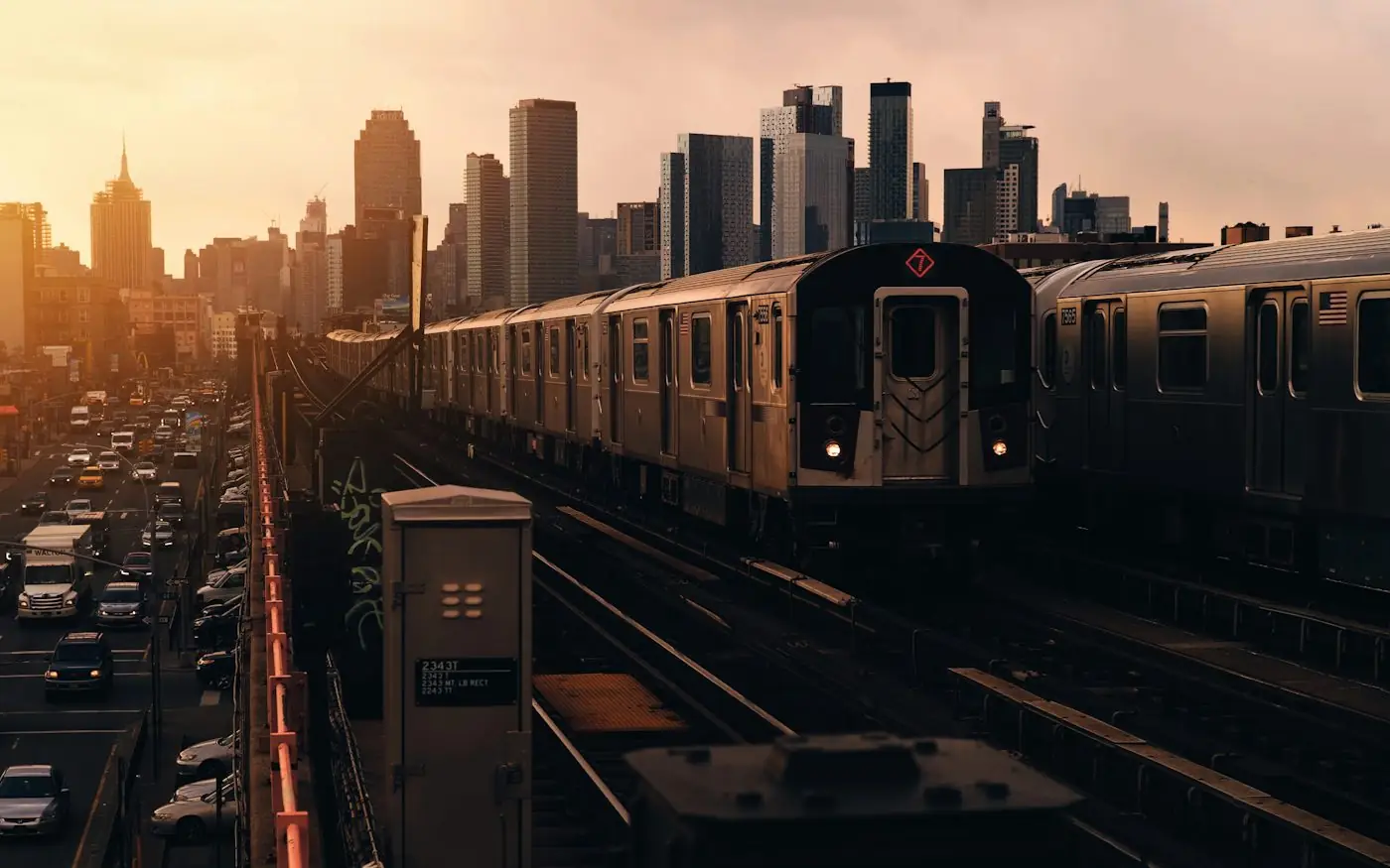 Elevated train tracks leading toward a city skyline at sunset